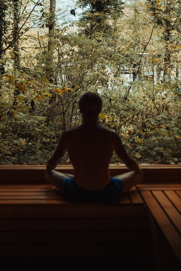 A man meditates in a serene forest environment, embodying peace and tranquility.