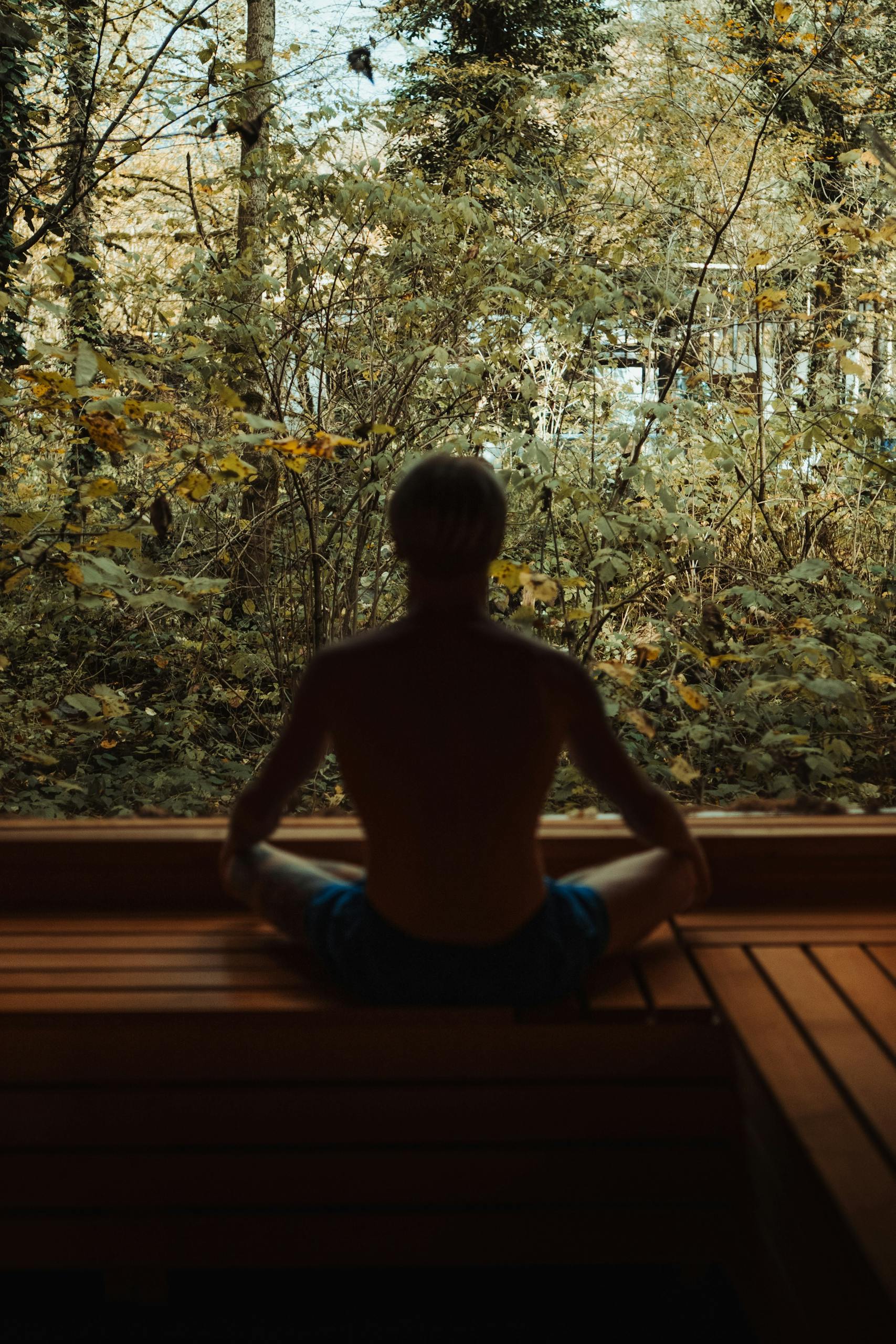 A man meditates in a serene forest environment, embodying peace and tranquility.