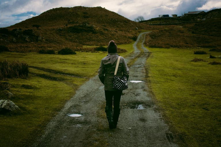 Person walking on a scenic countryside trail, embracing solitude and nature.
