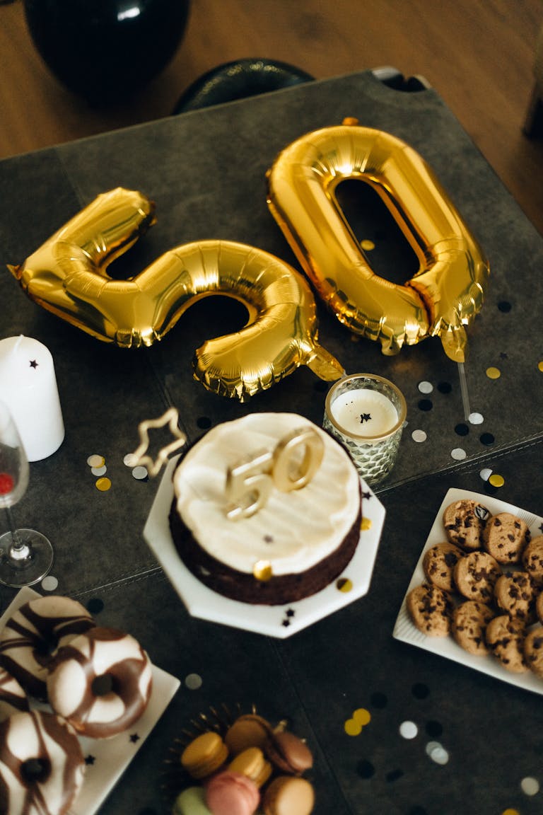 Stylish 50th birthday table with gold balloons, cake, and desserts. Perfect for milestone celebrations.